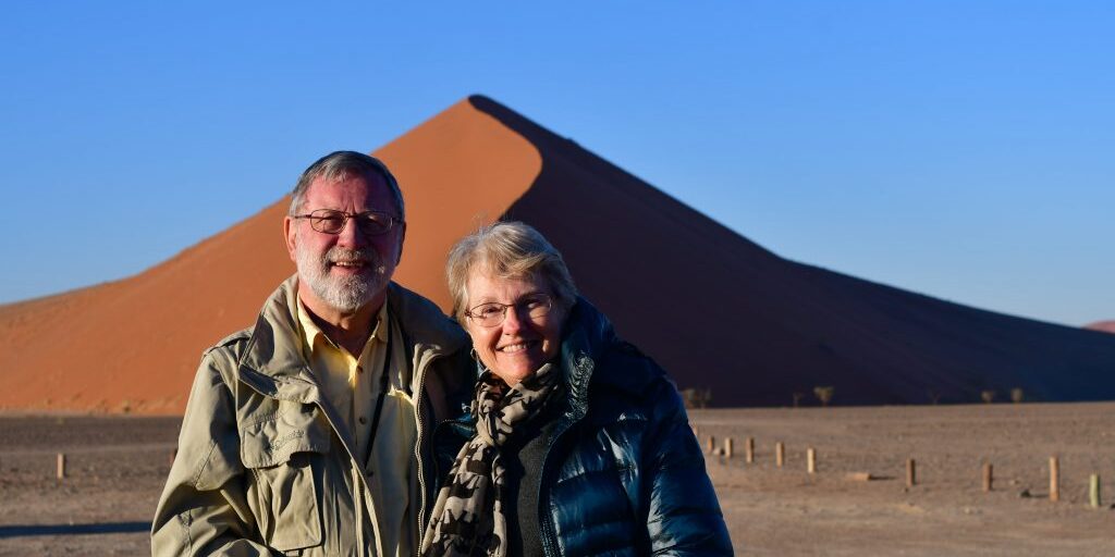 Dr. Gerald Hanson and his wife, Sue, pose in front of sand dunes during their travels in Namibia.